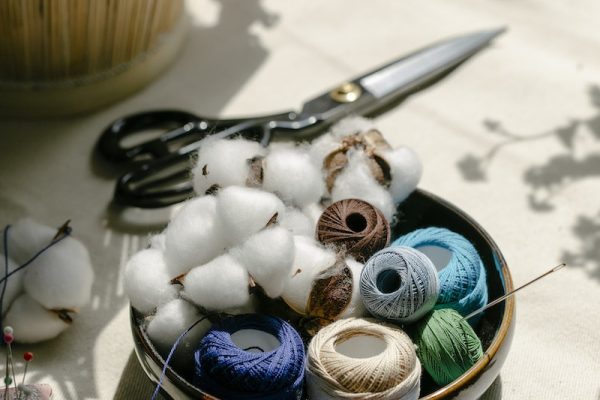Thread bobbins with scissors and needles placed on table in atelier